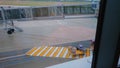 Baggage tractor with luggage passes through a pedestrian crossing near the airbridge in airport.