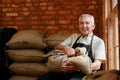 Bagged and tagged. Cropped portrait of a senior man holding a sack of coffee beans while sitting in a roastery.