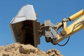 Excavator bucket over earth heap against a blue sky Royalty Free Stock Photo