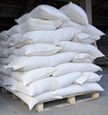 Bags of industrial cement are placed on wooden pallets. Royalty Free Stock Photo