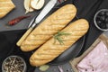 Baguette bread and ingredients for sandwich olives, tomatoes, lettuce, garlic and spices over dark background. Top view. Cooking Royalty Free Stock Photo