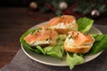 Baguette canapes with salmon and cream cheese on a plate with lettuce, dark rustic wooden table with Christmas decorations, copy
