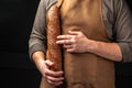 baguette in hand. bread in baker hands. bakery products on a dark background