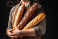 baguette in hand. bread in baker hands. bakery products on a dark background