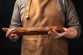 baguette in hand. bread in baker hands. bakery products on a dark background. The concept of baking bakery products