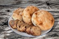 Pitta Bread Loaves And Baguette Bread Slices On Porcelain Plate Set On Old Weathered Knotted Picnic Table Grunge Surface