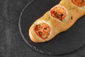 Baguette, long bun with dried tomatoes, on slate stone plate round, dark background, selective focus