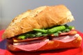 Baguette sandwich cut in half with ham, turkey breast, cheese, lettuce and tomatoes on a cutting board closeup Royalty Free Stock Photo