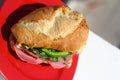 Baguette sandwich cut in half with ham, turkey breast, cheese, lettuce and tomatoes on a cutting board closeup Royalty Free Stock Photo