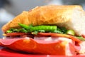 Baguette sandwich cut in half with ham, turkey breast, cheese, lettuce and tomatoes on a cutting board closeup Royalty Free Stock Photo