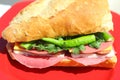 Baguette sandwich cut in half with ham, turkey breast, cheese, lettuce and tomatoes on a cutting board closeup Royalty Free Stock Photo