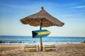 Bahamas flag on wooden arrow sign. There are two sun loungers and a sun umbrella on the beach. It is a tropical paradise with a