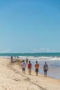 BAHIA, BRAZIL - June 27, 2019: Group of men walking under the hard sun in the sand full of seaweed near the blue sea of