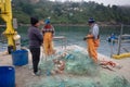 Three fishermen get out crabs from fishing net on pier