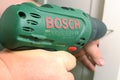 A man works with a Bosch rechargeable drill accumulator drill.