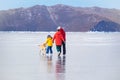 Baikal ice and a happy family skating with a dog. The concept of winter holidays and travel