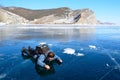Baikal lake, Russia, March, 13, 2017. Female tourist lying on the ice and looking through the ice on the bottom of the lake near O