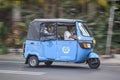 Bajaj or tuk tuk three wheeler powered by Compressed Natural Gas driving fast on the road blurry in motion