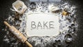 Bake word in flour with baking tools on dark background Royalty Free Stock Photo