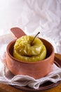 A baked apple in a clay pot on a linen cloth and wooden desk against white background Royalty Free Stock Photo