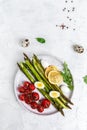 Baked asparagus with lemon, cherry tomatoes and boiled quail eggs. Vegetarian diet salad, lunch, breakfast, vertical image, place Royalty Free Stock Photo