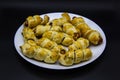 Baked ausages in the dough on a white plate against black background. Sausage Puff Pastry Buns.sausages wrapped in puff pastry and