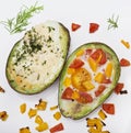 Baked avocado with eggs , cheese and vegetables on white background