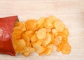 Baked BBQ potato chip bag spilling contents on a light wood table Royalty Free Stock Photo