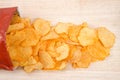 Baked BBQ potato chips spilling from bag on light wood table Royalty Free Stock Photo