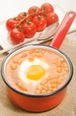 Baked beans with fried egg in a red enamel pot Royalty Free Stock Photo