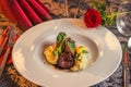 Baked beef with baby patizone, sauce and spinach served on white plate with flowers and champagne, romantic time on valentines day Royalty Free Stock Photo