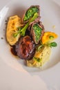 Baked beef with baby patizone, sauce and spinach served on white plate with flowers and champagne, romantic time on valentines day Royalty Free Stock Photo