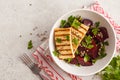 Baked beet salad with grilled tofu parsley and oil in a white bo