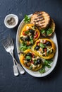 Baked bell peppers stuffed greek salad - delicious appetizers, snacks on a dark background