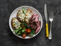 Baked blue cheese potatoes, beef steak and vegetable salad on a dark background, top view Royalty Free Stock Photo