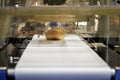 baked bread in food grade plastic bag on conveyor belt moves to seal in packing machine at production line of bakery manufacturing Royalty Free Stock Photo