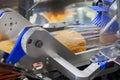 baked bread in food grade plastic bag on conveyor belt moves to seal in packing machine at production line of bakery manufacturing Royalty Free Stock Photo