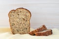 Baked bread with seeds on kitchen towel. Wooden background. Copy space, empty place. Sliced brown bread