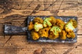 Baked Breaded broccoli on a wooden board with herbs. White wooden background. Top view