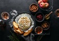 Baked brie served in a rustic manner with honey walnuts cranberry jam and rose wine,top down view