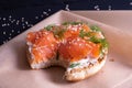 Baked bun, oiled with fresh cream, garnished with smoked fish trout and sprinkled with fresh dill and sesame seeds on parchment