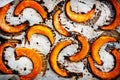 Baked caramelized pumpkin slices on parchment paper, autumn food. Rustic style. Top view