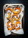 Baked caramelized pumpkin slices on parchment paper, autumn food. Rustic style. Top view