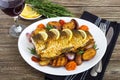 Baked carp with vegetables grilled on a white plate and a glass of red wine Royalty Free Stock Photo