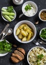 Baked cauliflower and potatoes, fresh cucumbers and herbs, sauces and spices on a dark stone background. Healthy vegetarian lunch Royalty Free Stock Photo