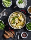 Baked cauliflower and potatoes in one pot, fresh cucumbers and herbs, sauces and spices on a dark stone background. Healthy Royalty Free Stock Photo