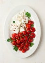 baked cherry tomatoes , with cheese, and spices, on a white plate, homemade, no people,