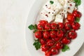 baked cherry tomatoes , with cheese, and spices, on a white plate, homemade, no people,