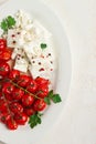 baked cherry tomatoes , with cheese, and spices, on a white plate, homemade, no people,