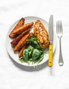 Baked chicken breast with sweet potatoes and spinach on a light background, top view. Balanced healthy lunch